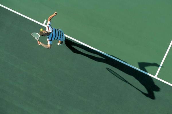 Tennisspieler mit Schläger auf Tennisplatz beim Aufschlag