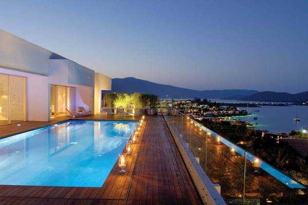 Abendlicher Blick auf einen Pool mit Aussicht auf das Meer vom Balkon des Elounda Beach Hotel & Villas.