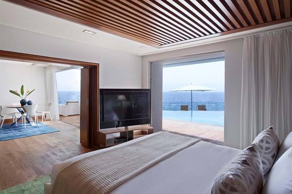 Elounda Beach Hotel & Villas Zimmer mit Meerblick, Bett, Fernseher, Tisch und Stühle.