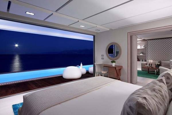 Schlafzimmer im Elounda Beach Hotel & Villas mit Meerblick und beleuchtetem Pool.