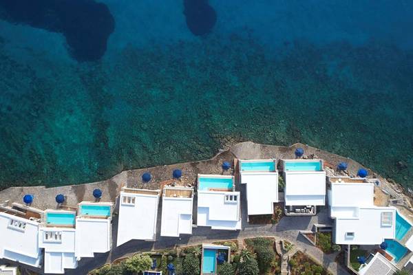 Luftaufnahme des Elounda Beach Hotel & Villas mit mehreren weißen Villen und Pools am Meer.