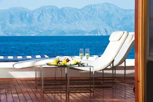 Terrasse im Elounda Beach Hotel & Villas mit Meerblick und zwei weißen Liegen.
