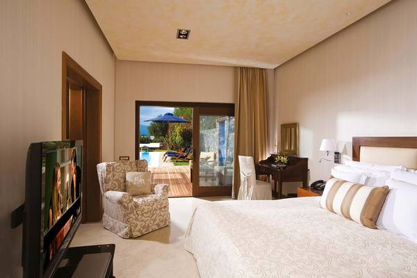 Schlafzimmer im Elounda Beach Hotel & Villas mit Fernseher, Bett und Zugang zur Terrasse