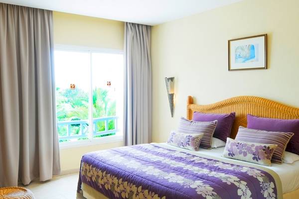 Schlafzimmer im Djerba Resort mit Bett, Blumenvase, Fernseher und Fenster mit Aussicht