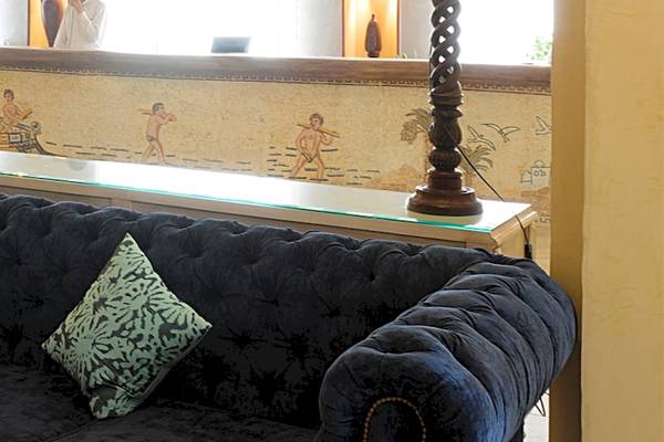 Lobby des Djerba Resorts mit schwarzem Sofa, zwei grünen Kissen und einer Glastheke.