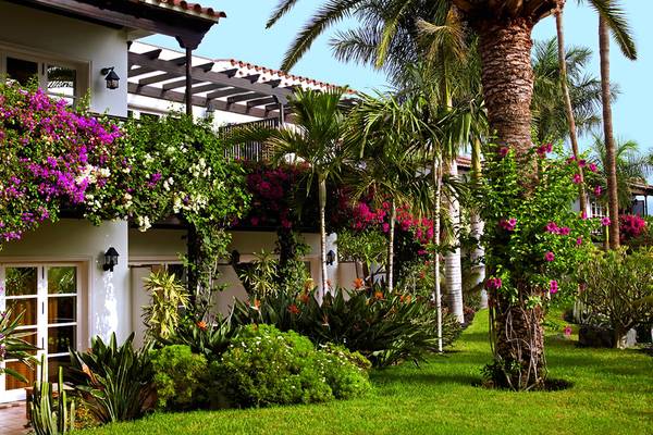 Außenbereich des Seaside Grand Hotel Residencia mit blühenden Pflanzen und Palmen