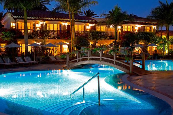 Beleuchteter Pool mit Brücke und Lounge-Sesseln im Seaside Grand Hotel Residencia bei Nacht