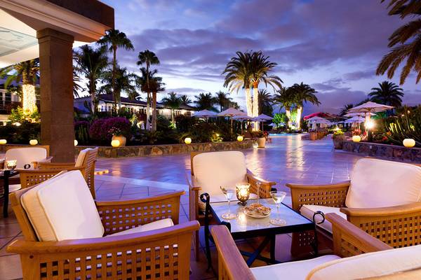 Lounge-Bereich des Seaside Grand Hotel Residencia bei Nacht mit beleuchteten Palmen und weichen Stühlen.
