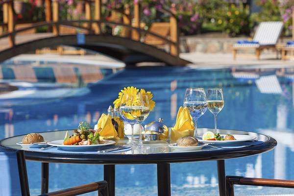 Tisch am Pool im Seaside Grand Hotel Residencia mit Gerichten und Getränken.