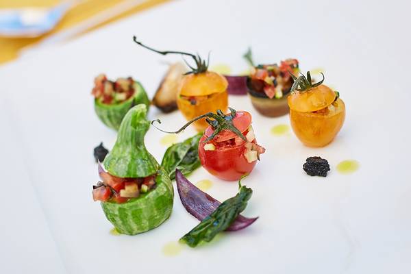 Ein Teller mit verschiedenen gefüllten Gemüsen, darunter Tomaten, Zucchini und Auberginen, dekorativ angerichtet.