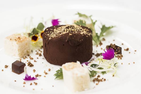 Schokoladenkuchen mit Golddekor und Beilagen auf weißem Teller