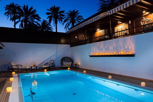Pool im Seaside Grand Hotel Residencia bei Nacht mit beleuchteten Kerzen und Lounge-Stühlen.