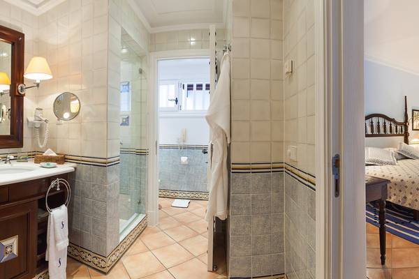 Badezimmer und Schlafzimmer im Seaside Grand Hotel Residencia mit blauen Fliesen und einem Bett.