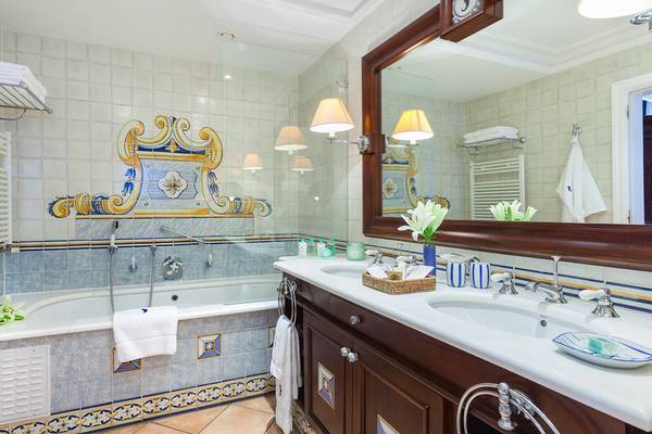 Badezimmer im Seaside Grand Hotel Residencia mit Badewanne, Waschbecken und Fliesenwand.