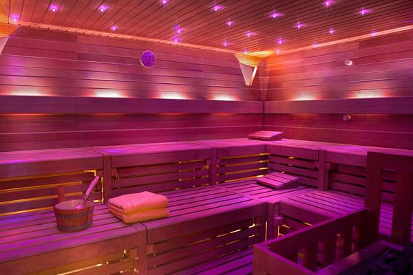 Innenansicht der Sauna im Seaside Grand Hotel Residencia mit Holzbänken und violetter Beleuchtung.