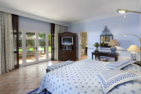 Schlafzimmer im Seaside Grand Hotel Residencia mit blauem Bett, Fernseher, und Gartenblick.