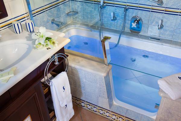 Badezimmer im Seaside Grand Hotel Residencia mit blauer Beleuchtung und Badewanne