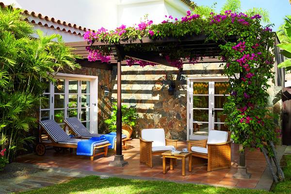 Terrasse des Seaside Grand Hotel Residencia mit Lounge-Möbeln, blauen Handtüchern und einem Tisch.
