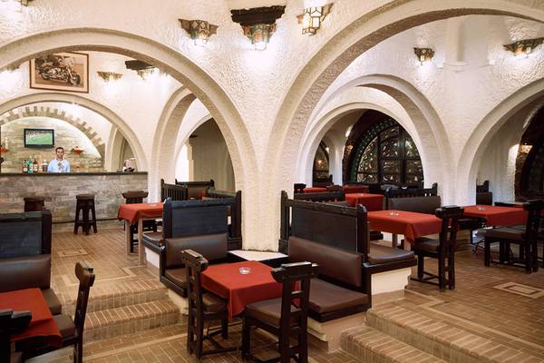 Innenansicht des Restaurants im Arabella Azur Beach Resort mit Bogendecken, roten Tischdecken und einem Barkeeper im Hintergrund.