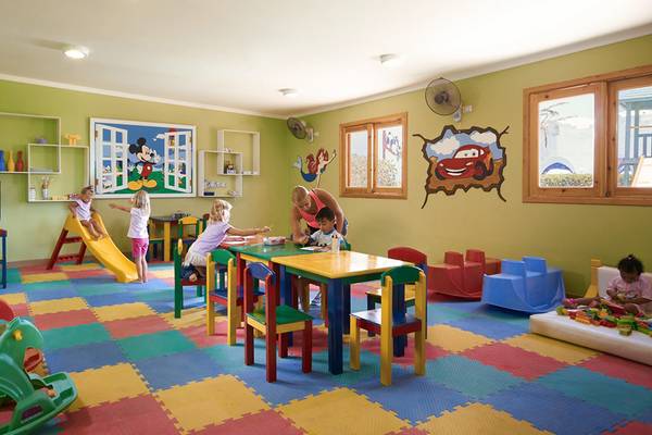 Kinderspielzimmer im Arabella Azur Beach Resort mit bunten Teppichfliesen, Spielzeug und einer Wand mit Disney-Motiven.