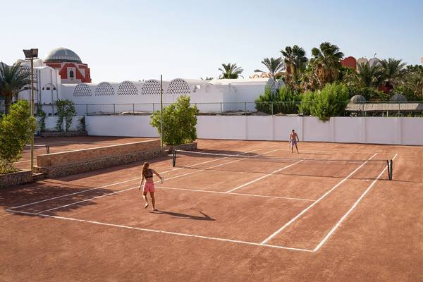 Tennisplatz im Arabella Azur Beach Resort mit zwei Spielern und Palmen im Hintergrund.