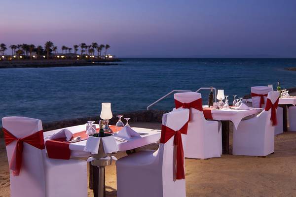 Außenrestauranttische des Arabella Azur Beach Resorts mit Blick auf das Meer bei Sonnenuntergang.
