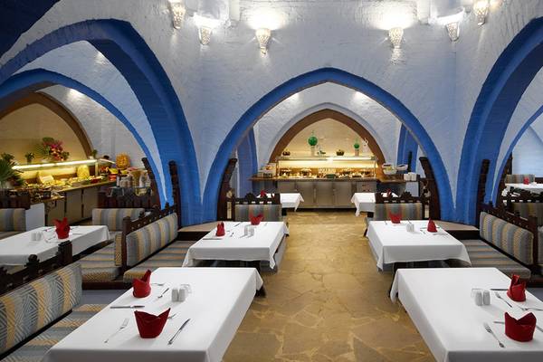 Innenansicht des Restaurants im Arabella Azur Beach Resort mit blauen Bögen und weißen Tischen.