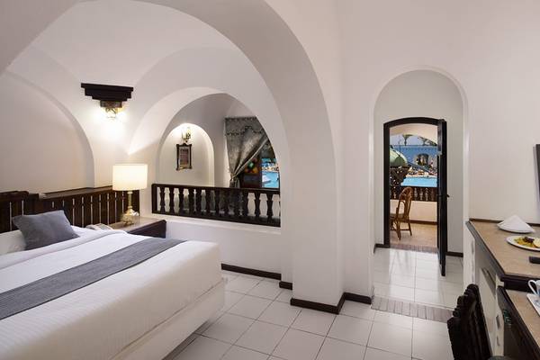 Ein Hotelzimmer im Arabella Azur Beach Resort mit einem Bett, Fernseher, Lampen und einem Balkon mit Blick auf den Pool.