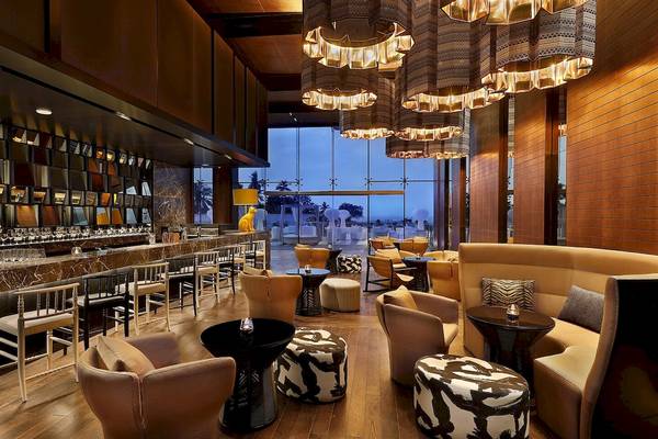 Loungebereich des W Muscat Hotels mit Holzboden, modernen Möbeln und großen Fenstern.