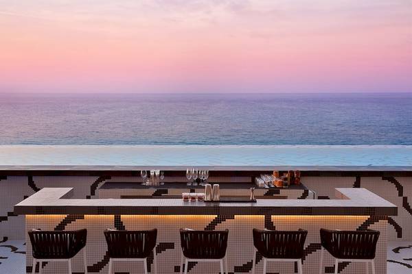 Bar des W Muscat Hotels mit Blick auf das Meer und Cocktails auf der Theke.