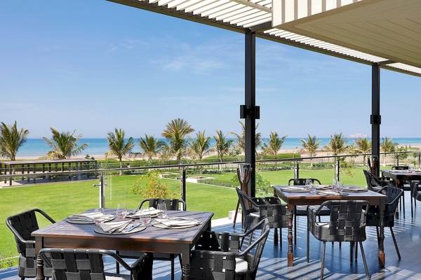 Außenterrasse des W Muscat Hotels mit Blick auf den Ozean und die Palmen