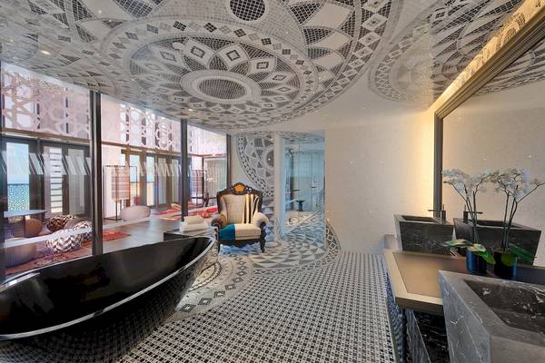 Schwarze Badewanne und gemusterter Teppich im Badezimmer des W Muscat Hotels