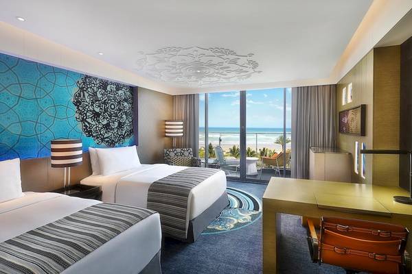Doppelzimmer im W Muscat Hotel mit Meerblick, modernen Möbeln und blauen Wandmustern.