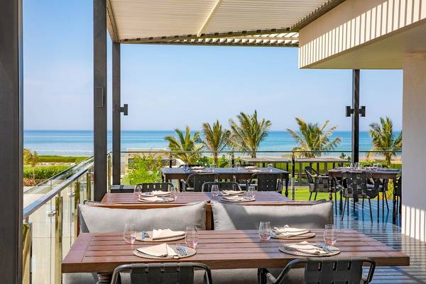 Terrasse des W Muscat Hotels mit Blick auf das Meer und Palmen