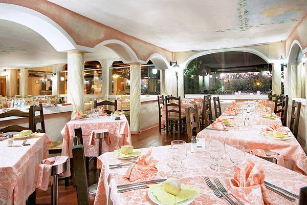 Innenbereich des Restaurants im Colonna Beach Hotel mit gedeckten Tischen und Stühlen.