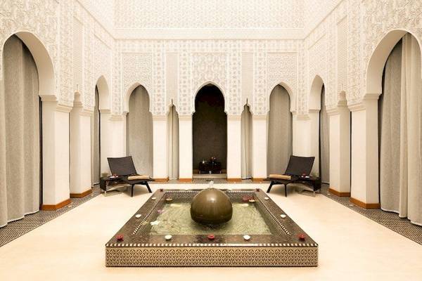 Loungebereich im Barcelo Palmeraie Hotel mit einem Brunnen und zwei Liegestühlen.