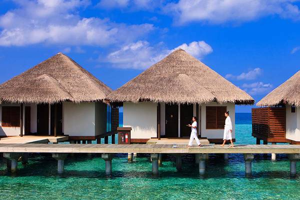 Drei traditionelle strohgedeckte Hütten auf Wasser im Velassaru Maldives Hotel