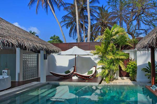 Private Pool Villa im Velassaru Maldives mit Swimmingpool, Liegestühlen und Sonnenschirm.