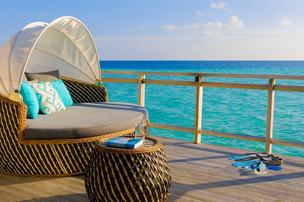 Velassaru Maldives Balkonsofa mit Meerblick, neben einem Buch und Schnorchelausrüstung.