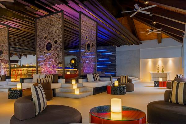 Loungebereich im Velassaru Maldives Hotel mit modernen Möbeln und dekorativen Lichtern.