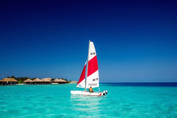 Ein Katamaran mit der Nummer 843 und dem Namen K3 segelt im Meer vor dem Velassaru Maldives Hotel.