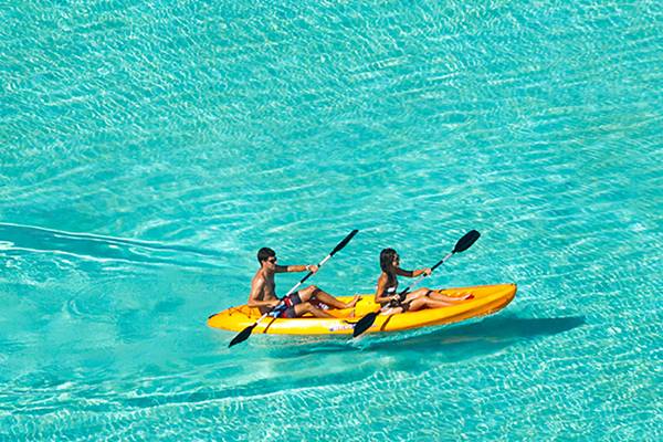 Zwei Personen paddeln in einem gelben Kajak im Ozean auf Velassaru Maldives.