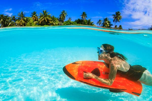Eine Frau schnorchelt im kristallklaren Wasser vor dem Hotel Velassaru Maldives.