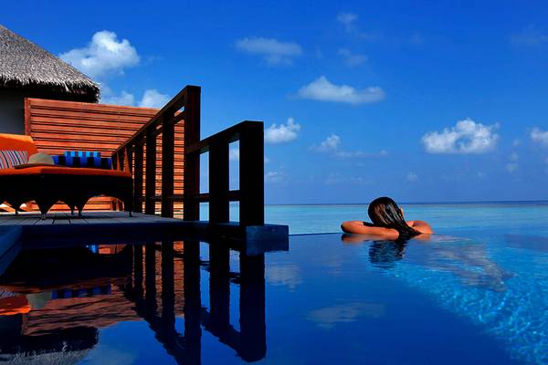Eine Frau entspannt sich im Infinity-Pool des Velassaru Maldives mit Blick auf den Ozean.