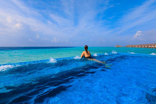 Eine Frau genießt das Schwimmen im blauen Pool des Velassaru Maldives.