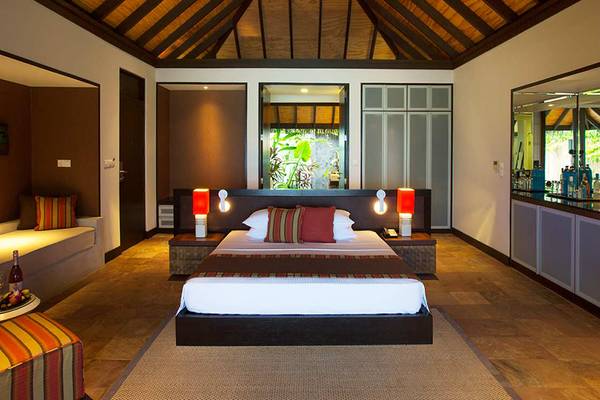 Schlafzimmer im Velassaru Maldives Hotel mit einem Bett, Nachttischen und einem geräumigen Innenraum.