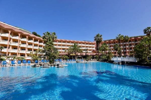 Außenbereich des Puerto Palace Hotels mit großem Swimmingpool und Sonnenliegen.