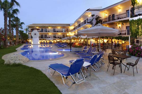 Pool-Lounge-Bereich des Almyrida Beach Hotels bei Nacht mit blauen Liegestühlen und Schirmen.