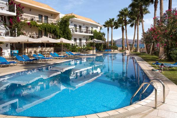 Pool neben dem Almyrida Beach Hotel mit Sonnenliegen und Palmen.