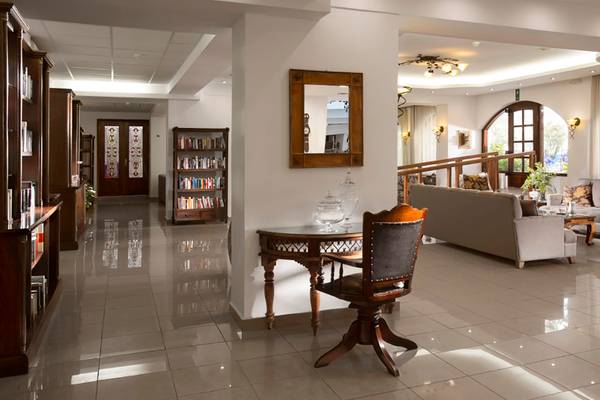 Innenansicht der Lobby des Almyrida Beach Hotels mit Bücherregal, Tisch und Sofa.